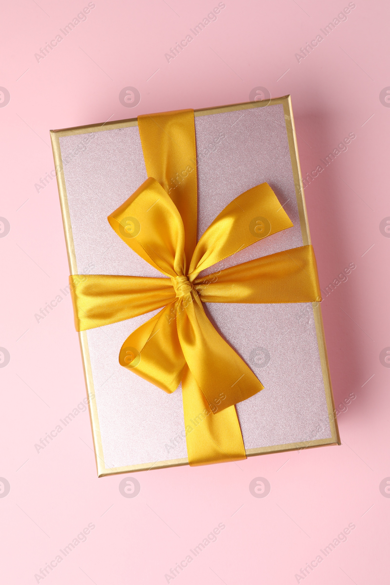Photo of Beautiful gift box with bow on pink background, top view