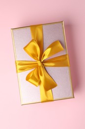 Photo of Beautiful gift box with bow on pink background, top view