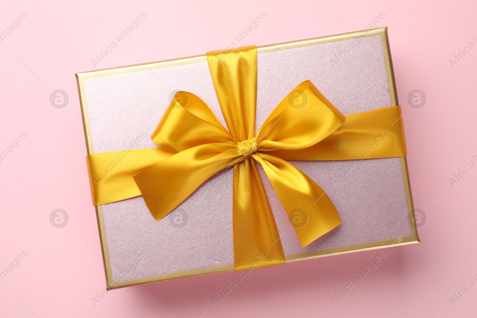 Beautiful gift box with bow on pink background, top view Photo of Beautiful gift box with bow on pink background, top view