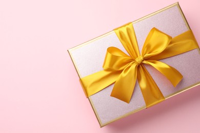 Photo of Beautiful gift box with bow on pink background, top view. Space for text