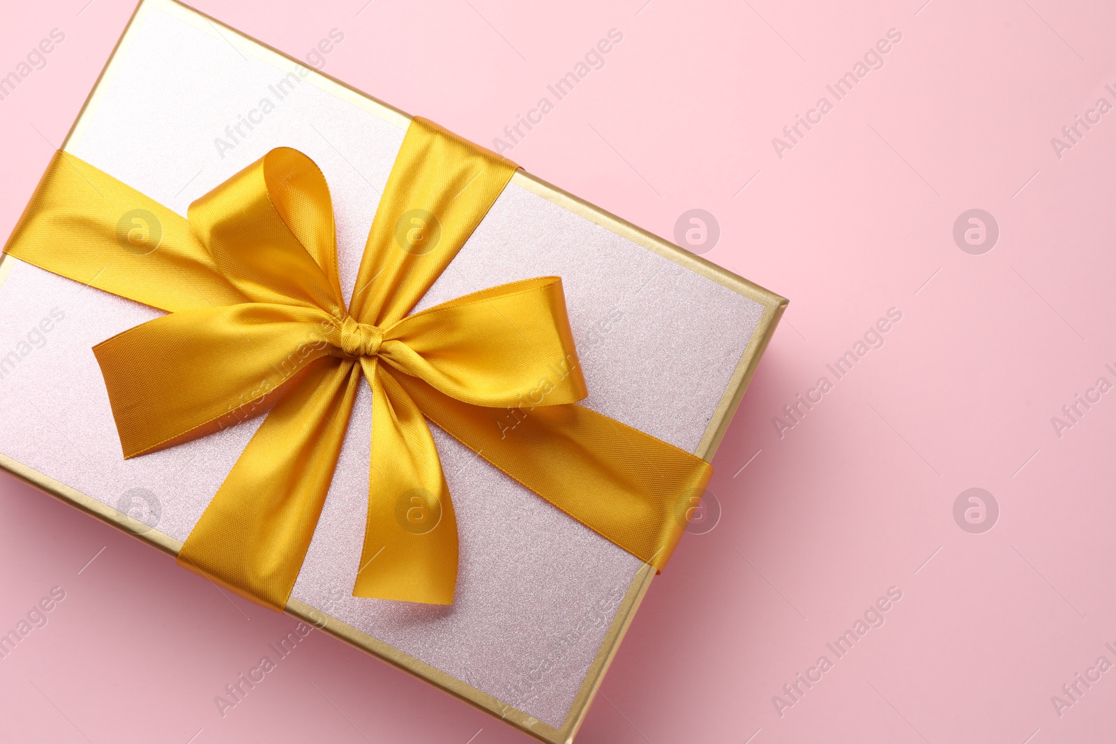 Photo of Beautiful gift box with bow on pink background, top view. Space for text