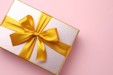 Photo of Beautiful gift box with bow on pink background, top view. Space for text