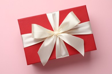 Photo of Beautiful gift box with bow on pink background, top view