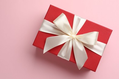 Photo of Beautiful gift box with bow on pink background, top view