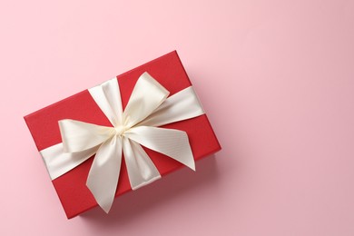 Photo of Beautiful gift box with bow on pink background, top view. Space for text