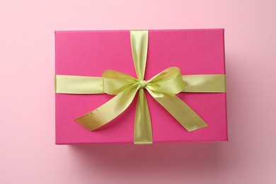 Photo of Beautiful gift box with bow on pink background, top view