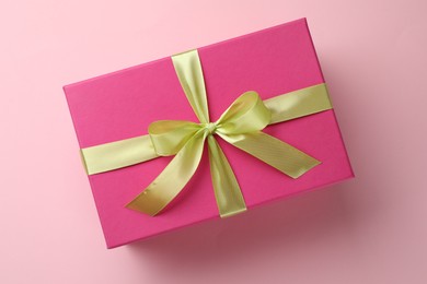 Photo of Beautiful gift box with bow on pink background, top view