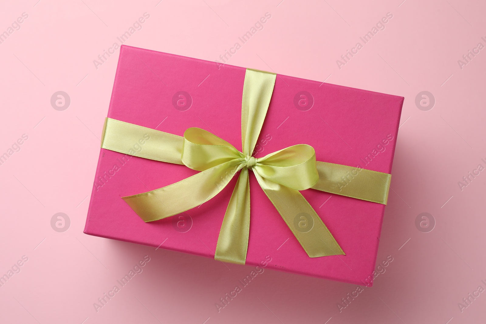 Photo of Beautiful gift box with bow on pink background, top view