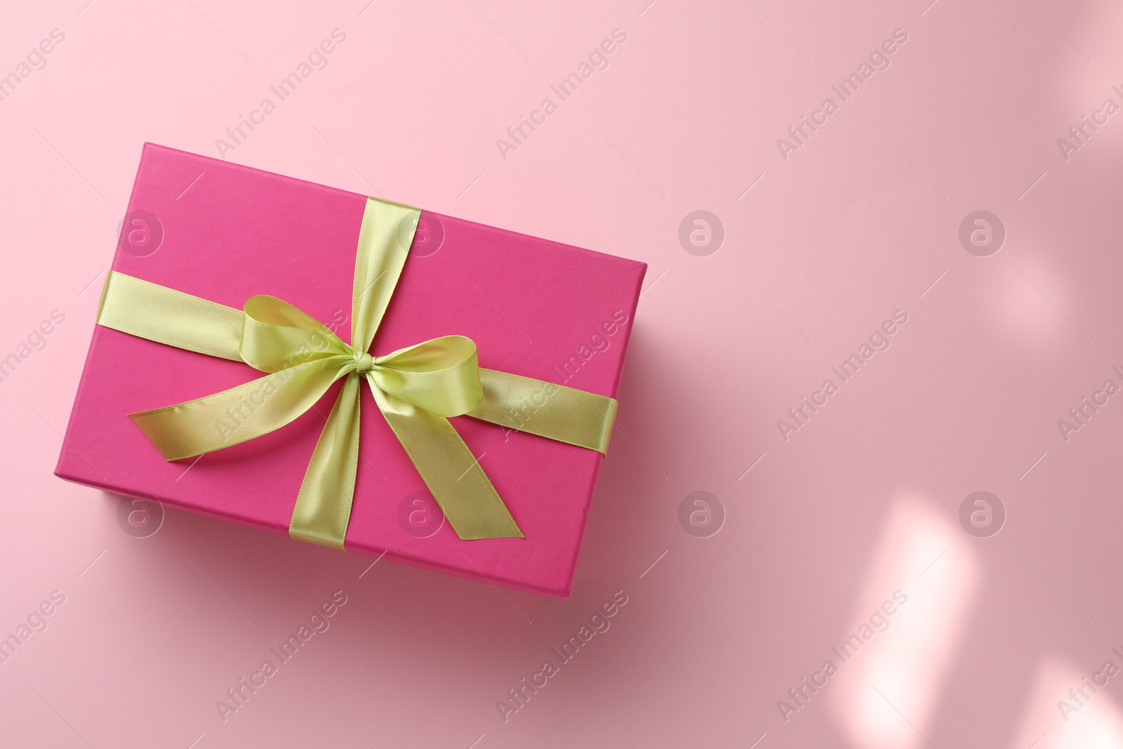 Beautiful gift box with bow on pink background, top view. Space for text Photo of Beautiful gift box with bow on pink background, top view. Space for text