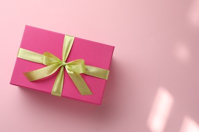 Photo of Beautiful gift box with bow on pink background, top view. Space for text