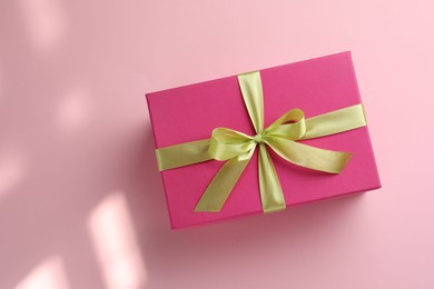 Photo of Beautiful gift box with bow on pink background, top view. Space for text