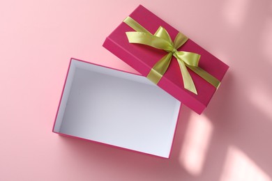Photo of Open gift box with beautiful lid on pink background, top view