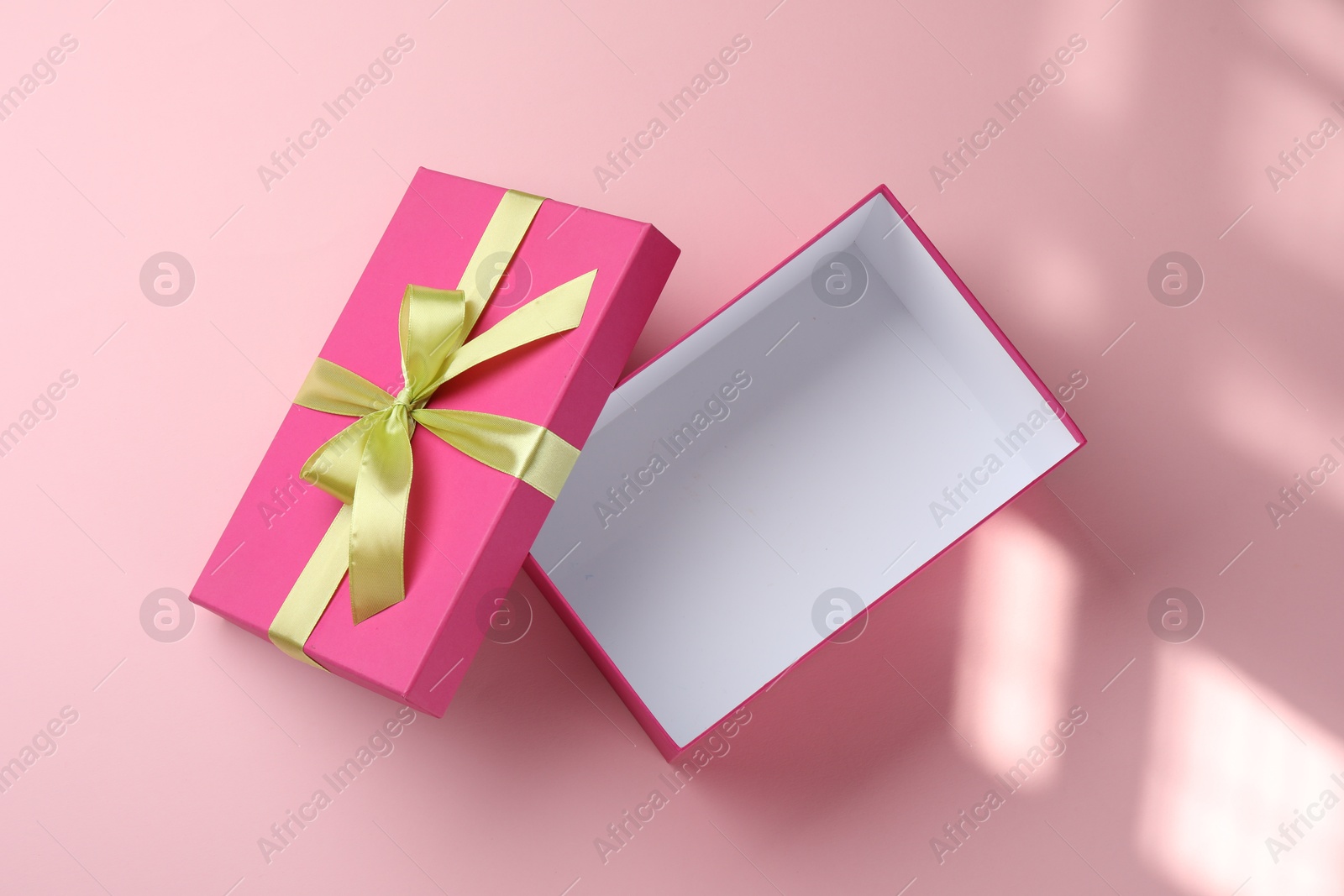 Photo of Open gift box with beautiful lid on pink background, top view