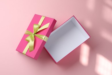 Photo of Open gift box with beautiful lid on pink background, top view