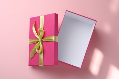 Photo of Open gift box with beautiful lid on pink background, top view