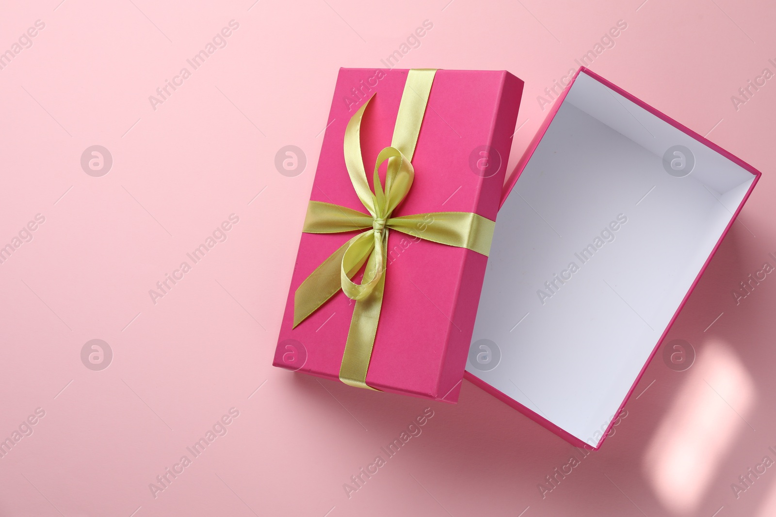 Photo of Open gift box with beautiful lid on pink background, top view. Space for text