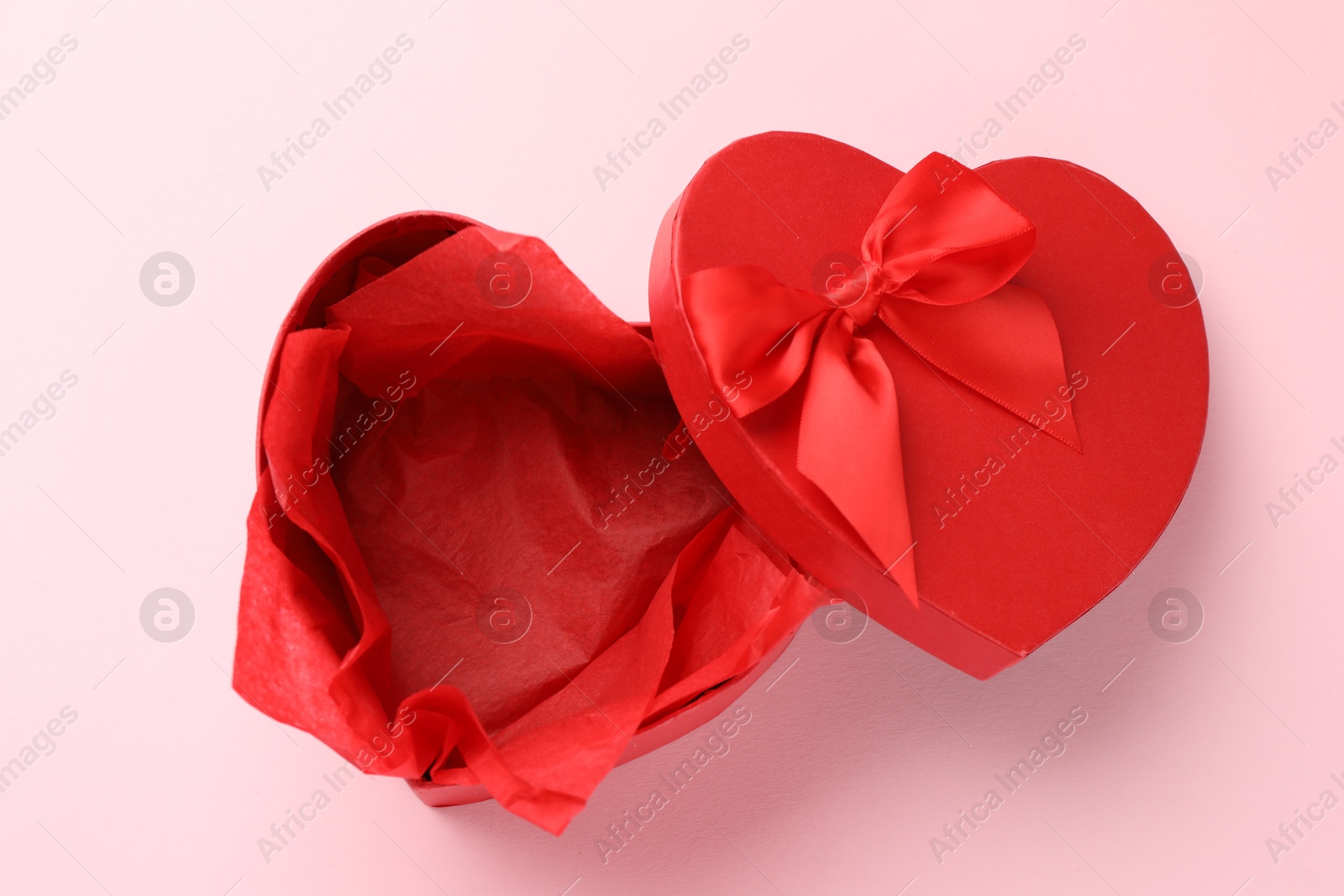 Photo of Heart-shaped gift box with beautiful lid on pink background, top view