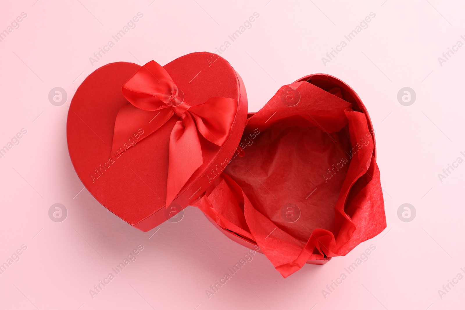 Photo of Heart-shaped gift box with beautiful lid on pink background, top view