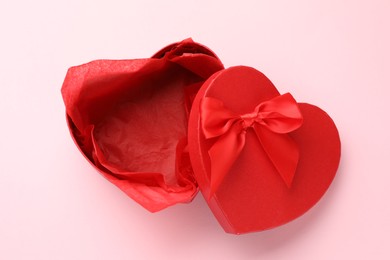 Photo of Heart-shaped gift box with beautiful lid on pink background, top view