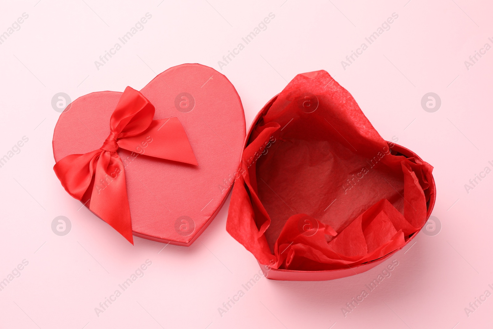 Photo of Heart-shaped gift box with beautiful lid on pink background, top view