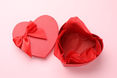 Photo of Heart-shaped gift box with beautiful lid on pink background, top view