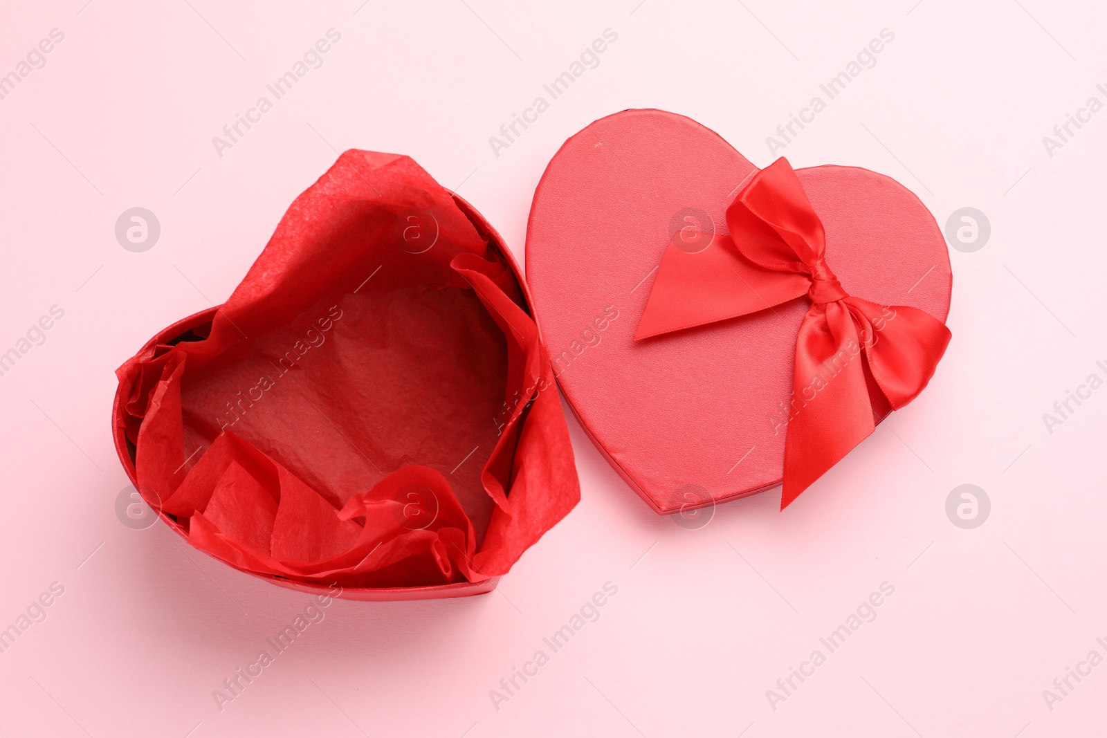 Photo of Heart-shaped gift box with beautiful lid on pink background, top view