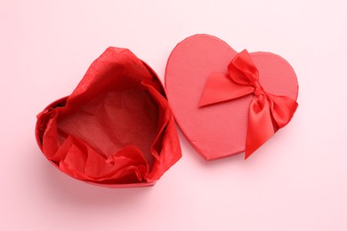 Photo of Heart-shaped gift box with beautiful lid on pink background, top view