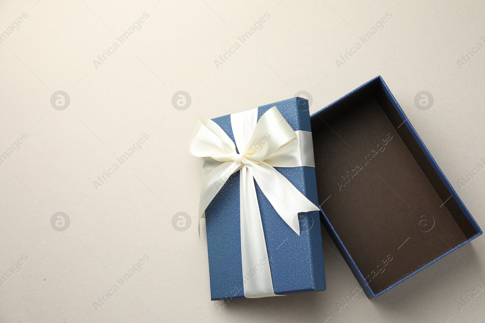 Photo of Open gift box with beautiful lid on light grey background, top view. Space for text