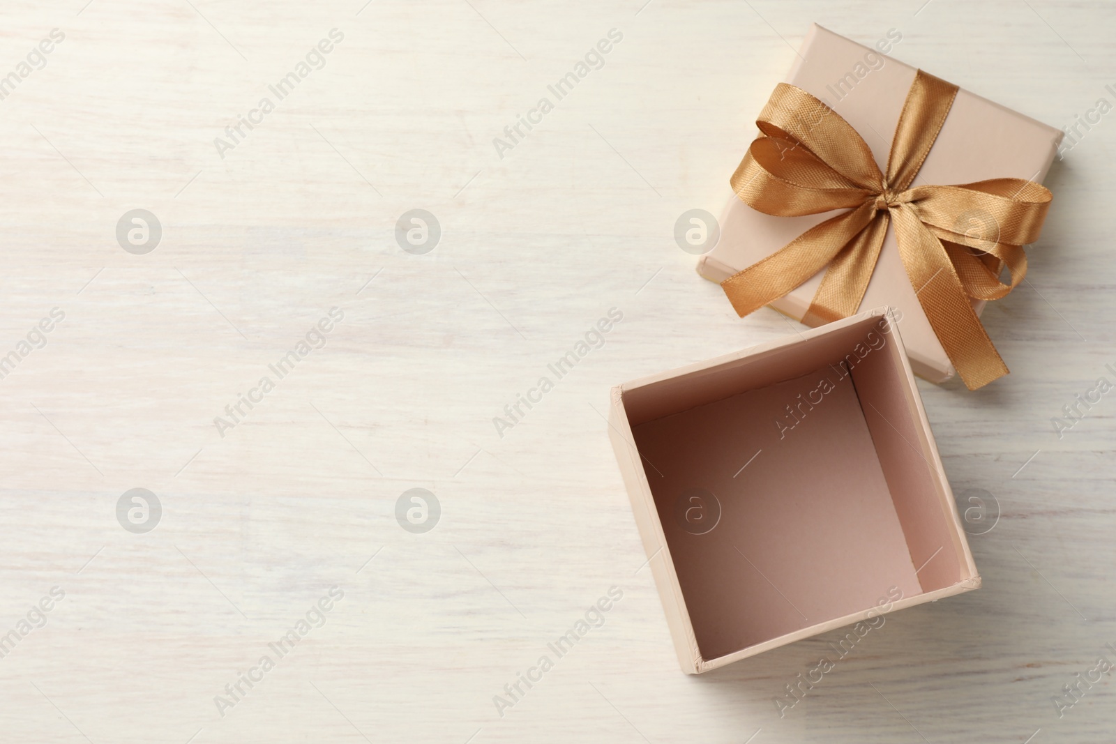 Photo of Open gift box with beautiful lid on white wooden table, top view. Space for text
