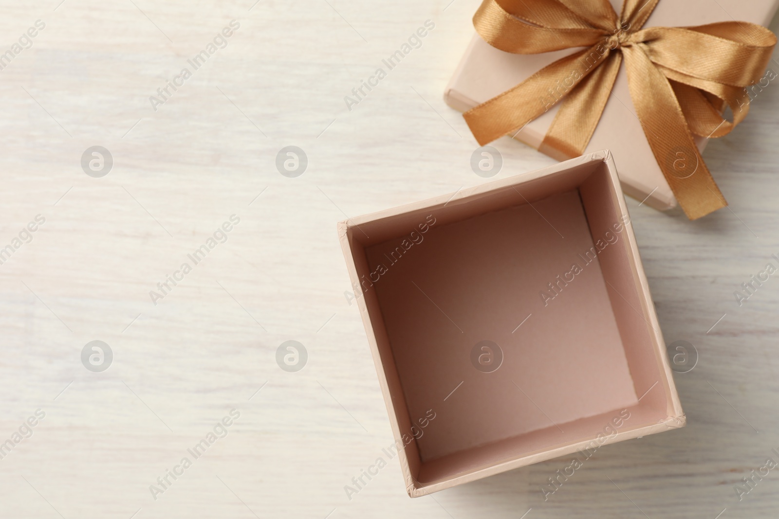 Photo of Open gift box with beautiful lid on white wooden table, top view. Space for text