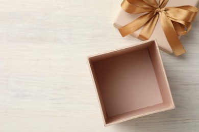 Photo of Open gift box with beautiful lid on white wooden table, top view. Space for text