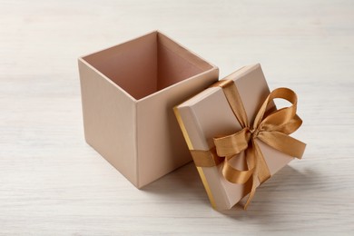 Photo of Open gift box with beautiful lid on white wooden table