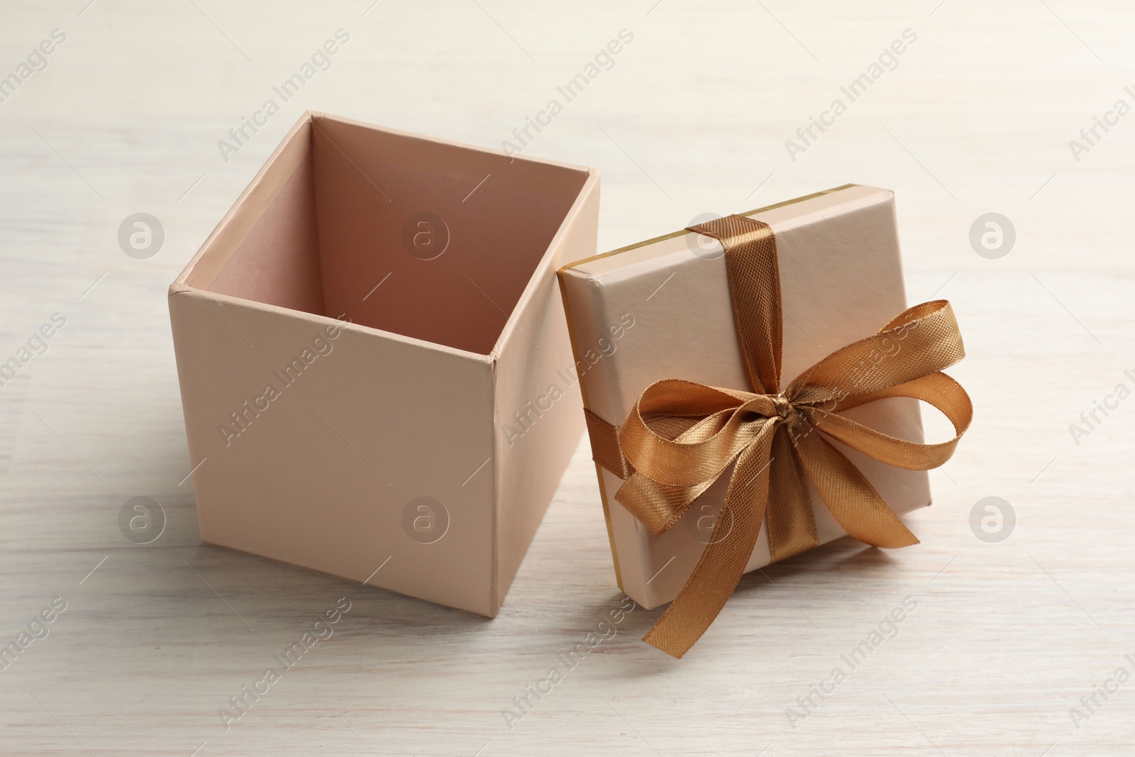 Photo of Open gift box with beautiful lid on white wooden table