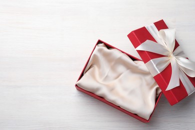 Photo of Open gift box with beautiful lid on white wooden table, top view. Space for text