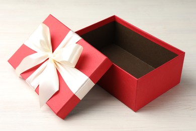 Photo of Open gift box with beautiful lid on white wooden table