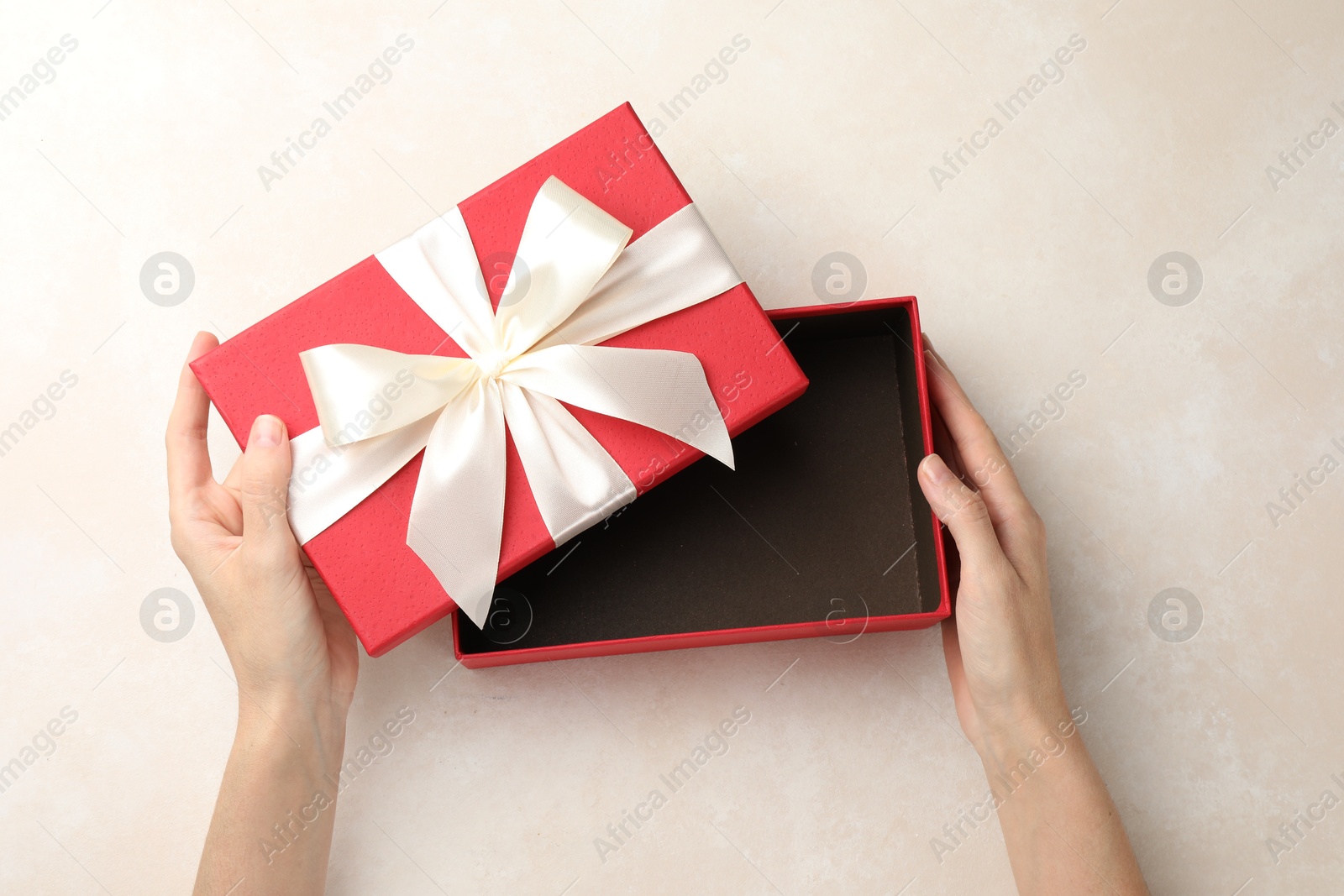 Photo of Woman opening gift box on light background, closeup