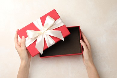 Photo of Woman opening gift box on light background, closeup