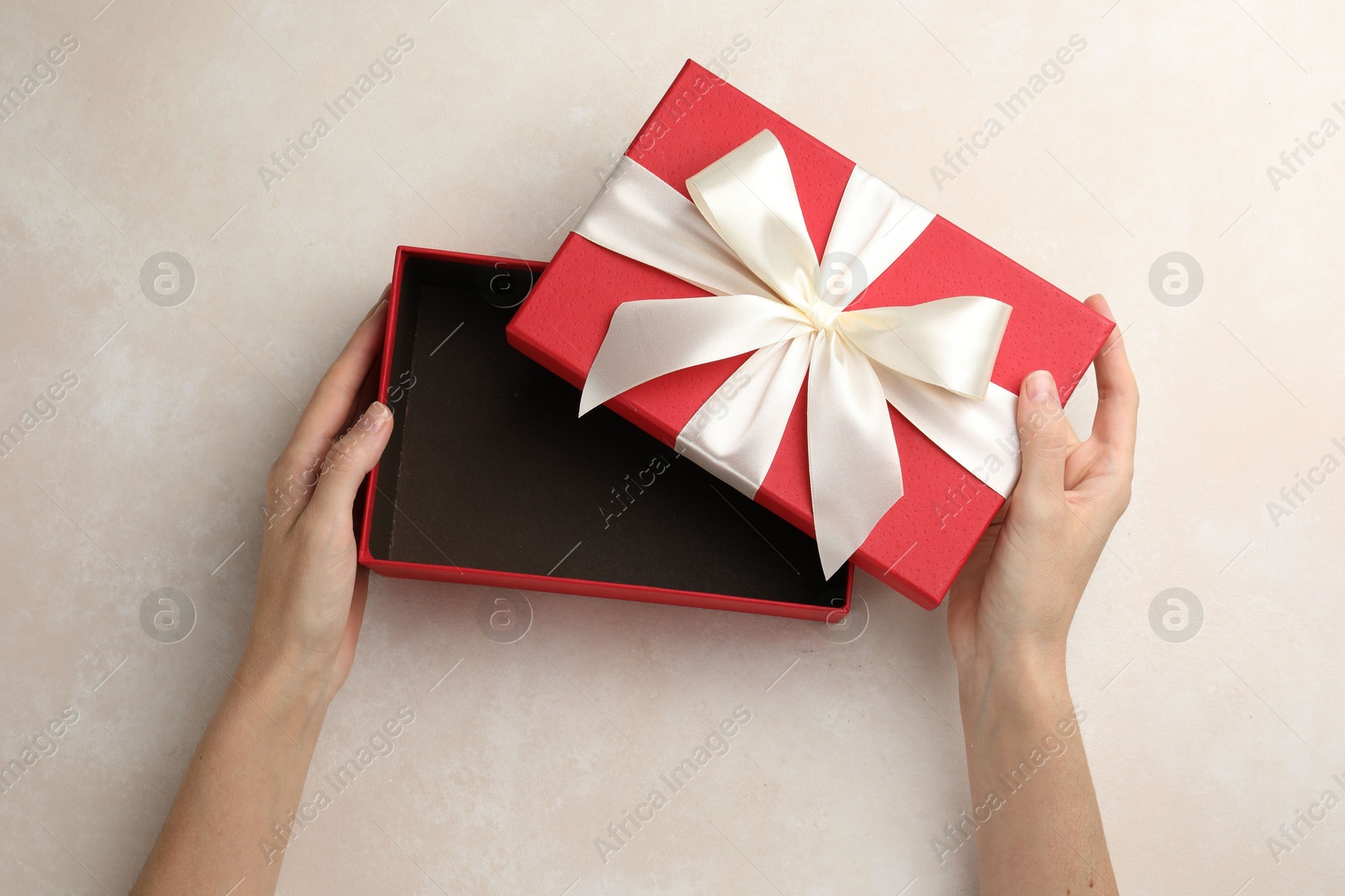 Woman opening gift box on light background, closeup Photo of Woman opening gift box on light background, closeup