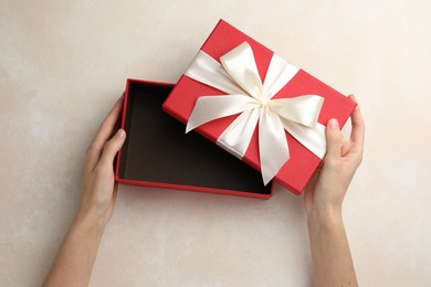 Photo of Woman opening gift box on light background, closeup