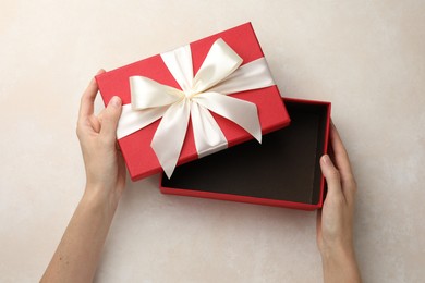 Photo of Woman opening gift box on light background, closeup