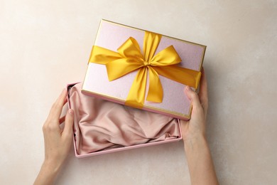Photo of Woman opening gift box on light background, closeup