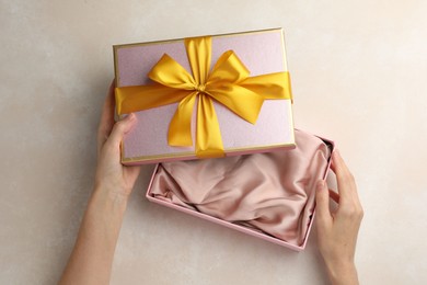 Photo of Woman opening gift box on light background, closeup