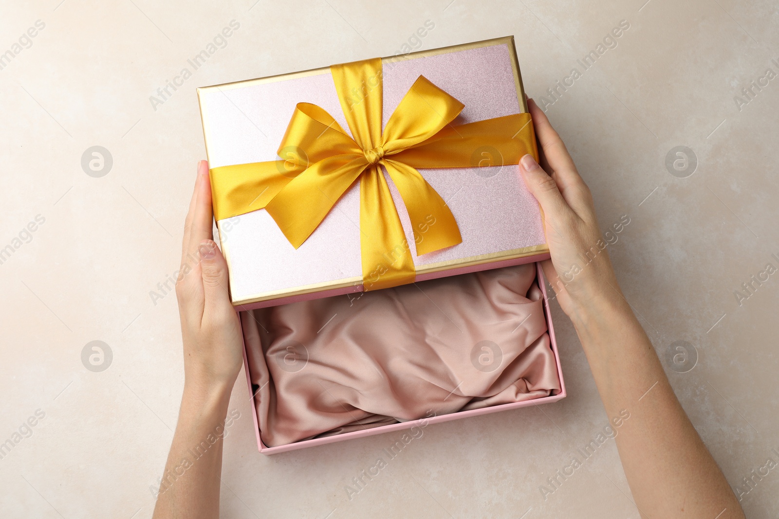 Photo of Woman opening gift box on light background, closeup