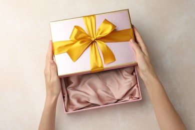 Photo of Woman opening gift box on light background, closeup