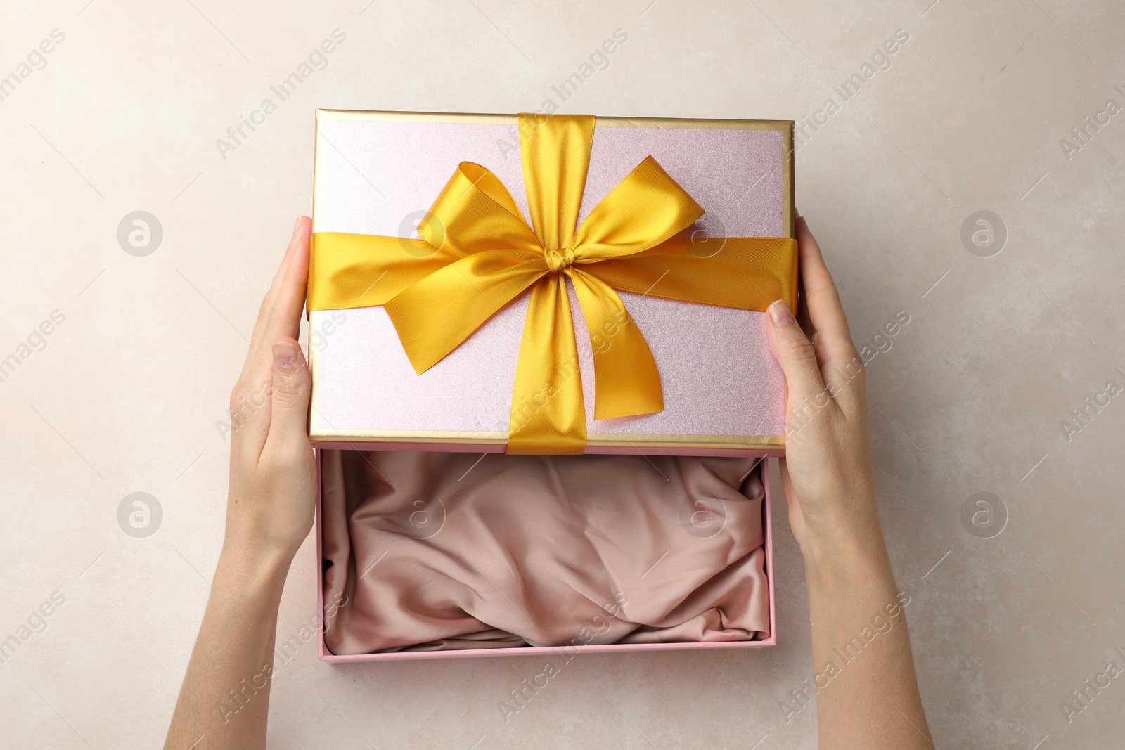 Photo of Woman opening gift box on light background, closeup