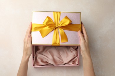 Photo of Woman opening gift box on light background, closeup