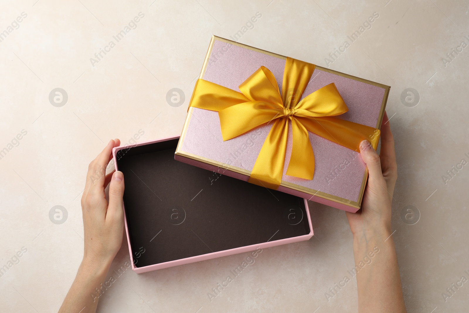 Photo of Woman opening gift box on light background, closeup