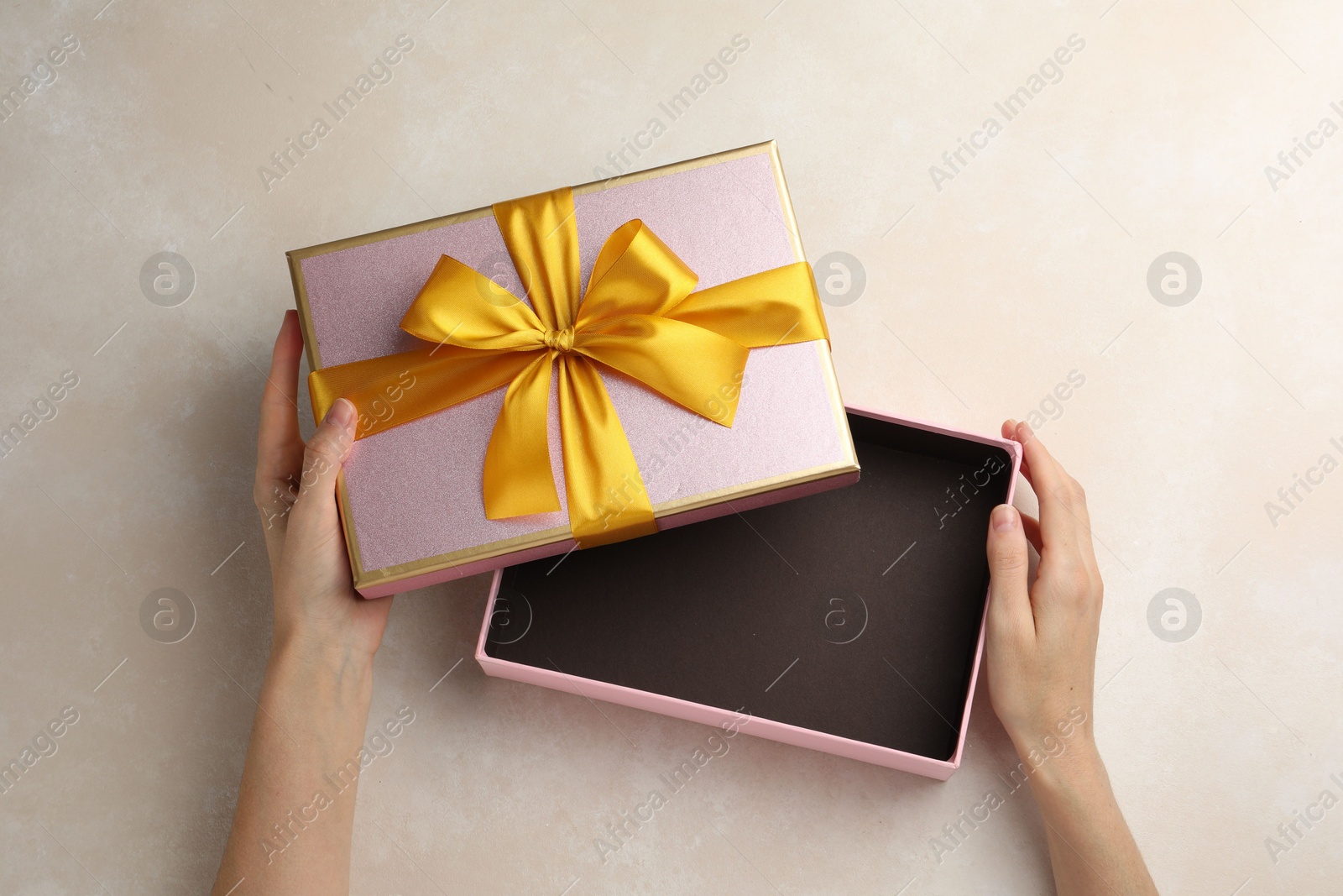 Photo of Woman opening gift box on light background, closeup