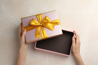 Photo of Woman opening gift box on light background, closeup