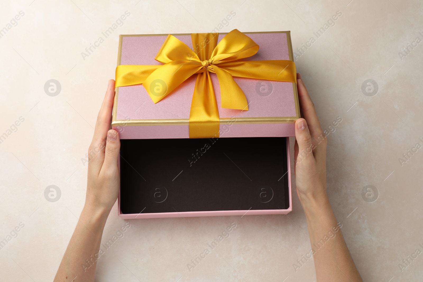 Photo of Woman opening gift box on light background, closeup